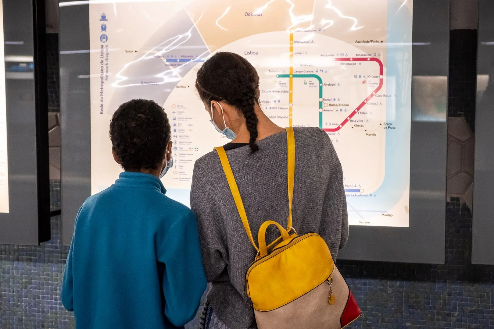 A woman and child, seen from behind, study the Lisbon Metro network map. Photograph by Gil Ribeiro.